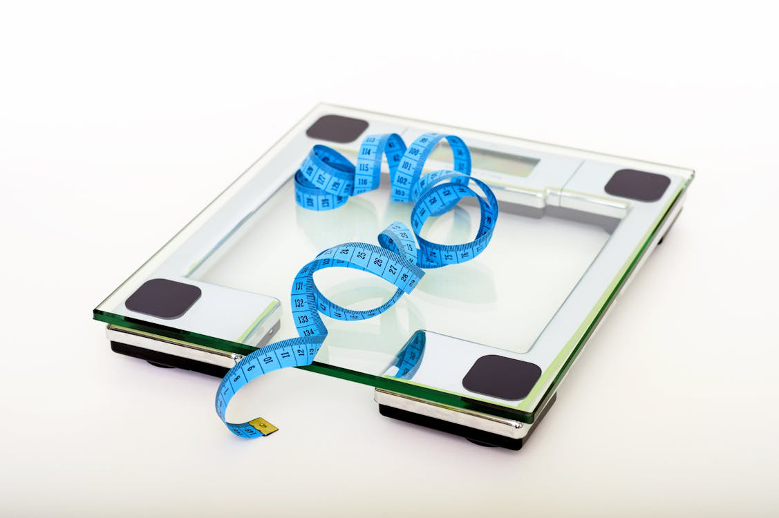 A weighing scale with a measuring tape over it